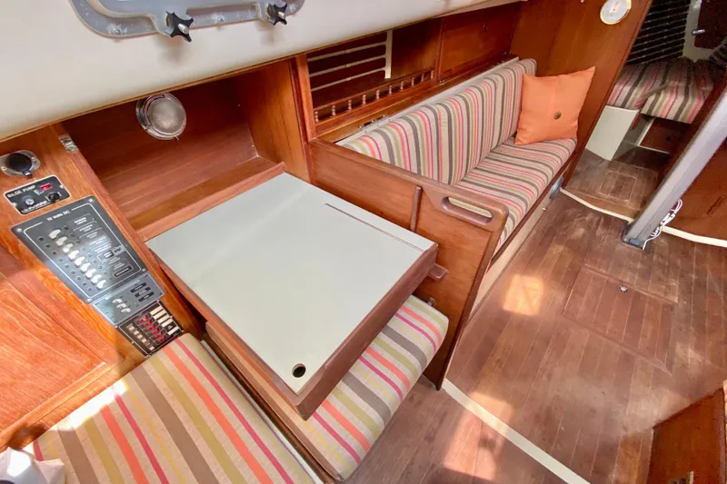Slide: The Image of 1986 Bayfield 32 yacht interior with striped seating, wooden paneling, and control panel. - 30