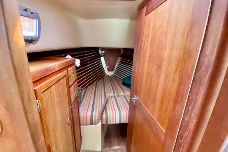 Slide: The Image of 1986 Bayfield 32 sailboat cabin with striped bedding and wooden cabinetry. - 37