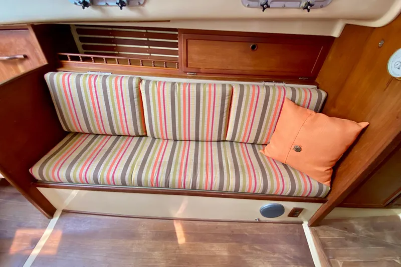 Slide: The Image of 1986 Bayfield 32 interior with striped cushions and orange pillow on wooden bench. - 43