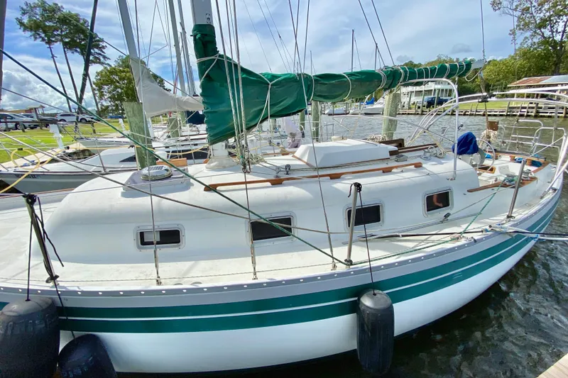 Slide: The Image of 1986 Bayfield 32 sailboat docked, featuring green sail cover and white hull. - 5