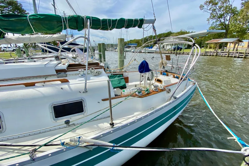 Slide: The Image of 1986 Bayfield 32 sailboat docked at a marina, featuring green accents and a spacious deck. - 6