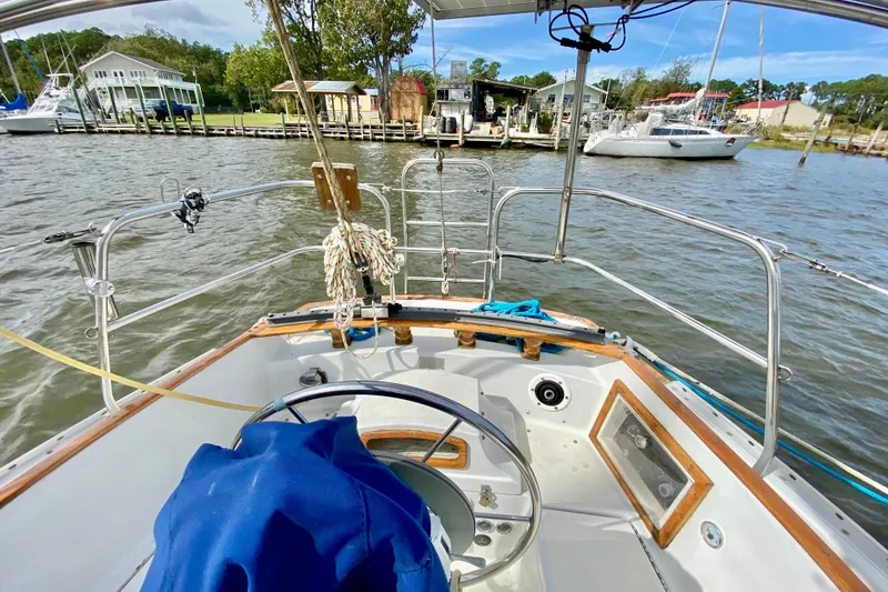 Slide: The Image of 1986 Bayfield 32 sailboat cockpit view, docked near waterfront homes. - 8
