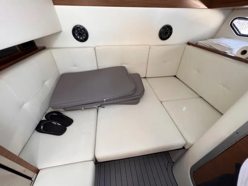 Slide: The Image of 2019 Cruisers Yachts 338 IO cabin with white seating, cushions, and flip-flops. - 30
