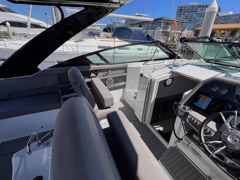 Slide: The Image of 2019 Cruisers Yachts 338 IO interior with modern helm, seating, and marina view. - 8