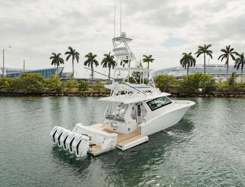 Slide: The Image of 2021 Scout 530 LXF luxury yacht with multiple engines, docked near palm trees. - 0