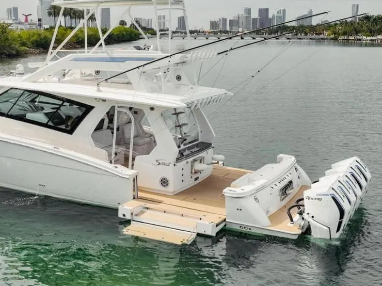 Slide: The Image of 2021 Scout 530 LXF luxury boat with multiple engines docked in a scenic marina. - 1