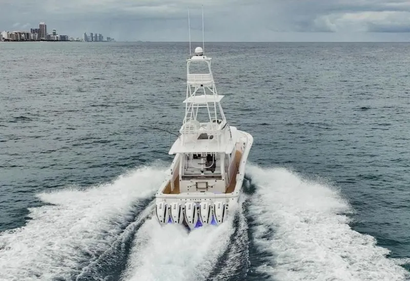 Slide: The Image of 2021 Scout 530 LXF boat cruising on open ocean with city skyline in background. - 6