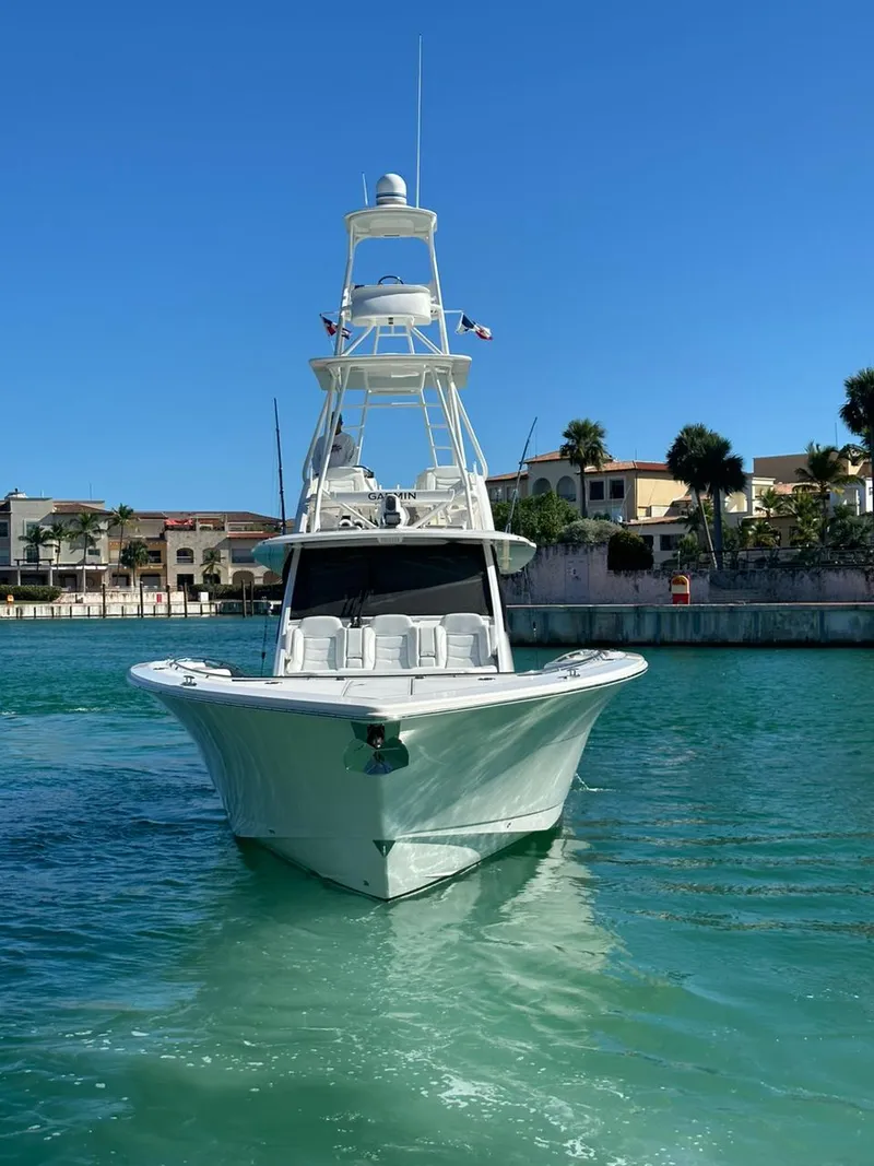 Slide: The Image of 2021 Scout 530 LXF boat on clear blue water near waterfront homes. - 8