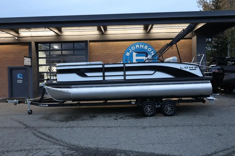 The Image of 2026 Lowe SS 230 CL pontoon boat on trailer outside dealership. - 1