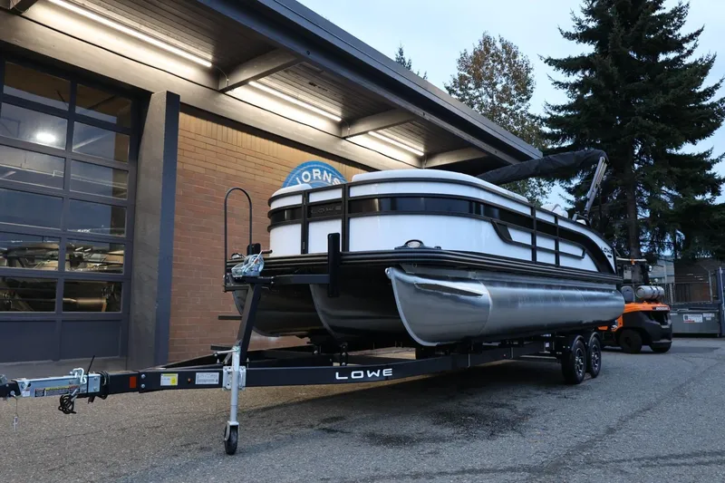 Slide: The Image of 2026 Lowe SS 230 CL pontoon boat on trailer outside a garage. - 14