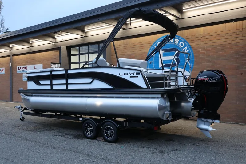 Slide: The Image of 2026 Lowe SS 230 CL pontoon boat on trailer, parked outside a building. - 3