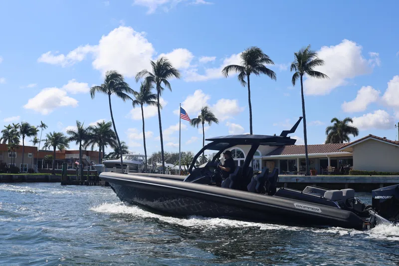 Slide: The Image of 2025 Skipper-BSK 34 boat cruising near palm trees and waterfront homes. - 7