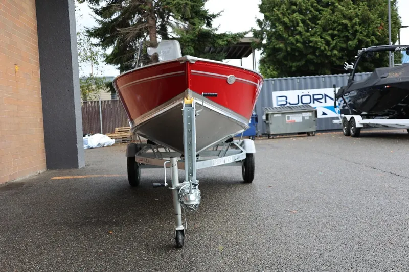 Slide: The Image of 2026 Lund 1400 Fury SS boat on trailer, parked outdoors, red hull, overcast day. - 13