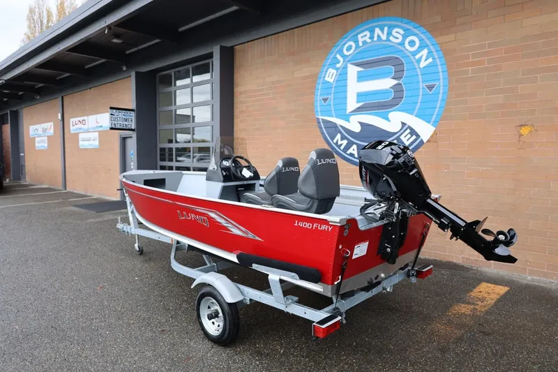 Slide: The Image of 2026 Lund 1400 Fury SS boat in red, parked outside Bjornson Marine. - 3