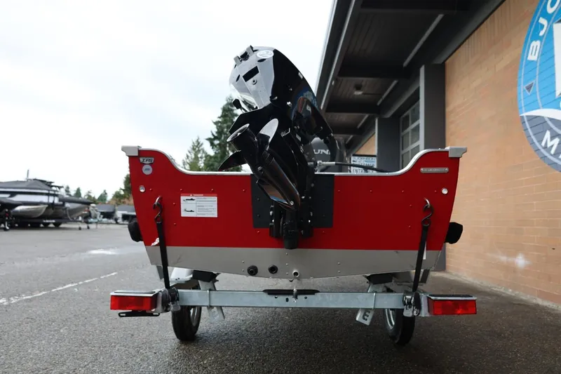 Slide: The Image of 2026 Lund 1400 Fury SS boat on trailer, rear view, red exterior, parked outdoors. - 6