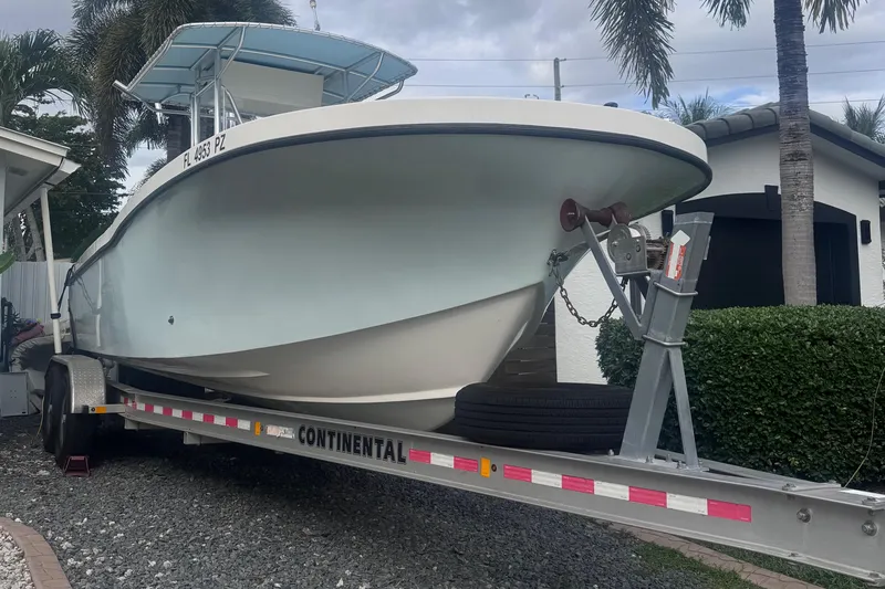 Slide: The Image of Dusky 278 boat on trailer, parked outdoors, surrounded by palm trees. - 3