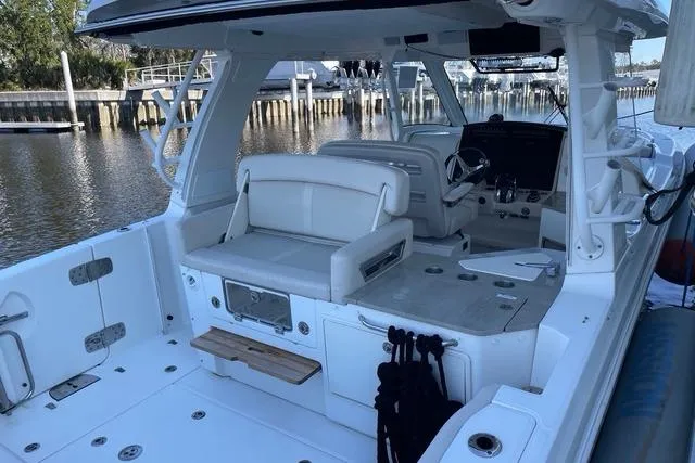 Slide: The Image of 2020 Boston Whaler 350 Realm boat interior with seating and helm, docked by the water. - 11