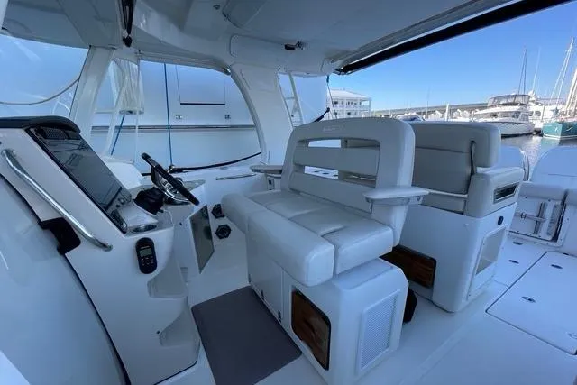 Slide: The Image of 2020 Boston Whaler 350 Realm interior with helm and seating, docked at marina. - 7