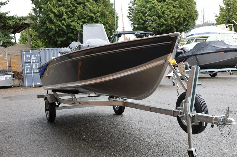 Slide: The Image of 2026 Lund 1600 Fury SS boat on trailer, parked outdoors near other boats. - 10