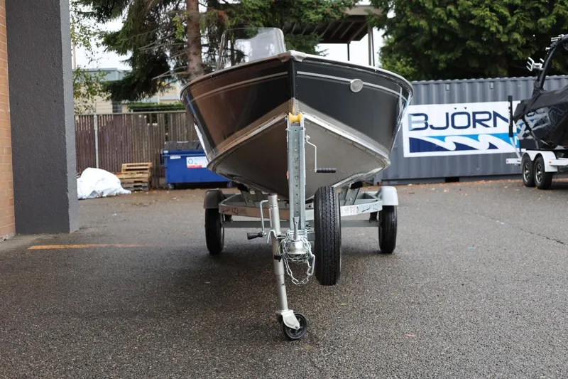 Slide: The Image of 2026 Lund 1600 Fury SS boat on trailer, parked outdoors near a container. - 12