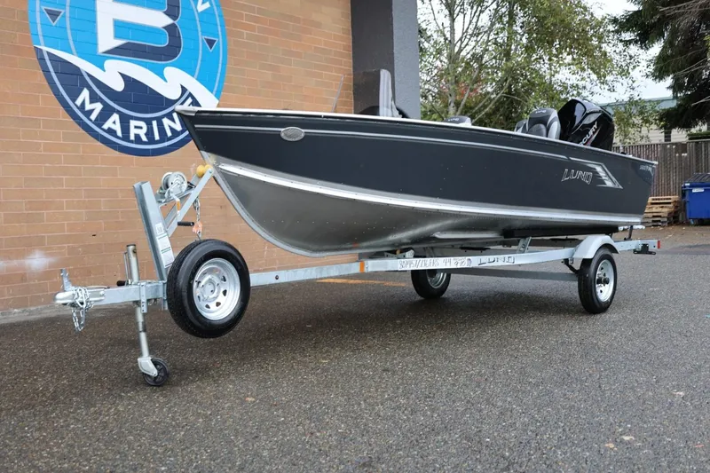 Slide: The Image of 2026 Lund 1600 Fury SS boat on trailer, parked outside a marine store. - 14