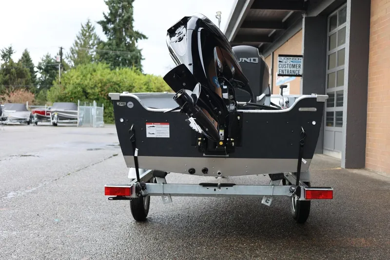 Slide: The Image of 2026 Lund 1600 Fury SS boat on trailer, rear view, parked outside dealership. - 6