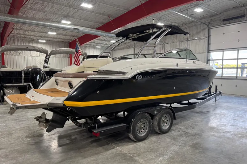 Slide: The Image of 2012 Cobalt 276 boat in showroom, black hull, yellow stripe, on trailer. - 3