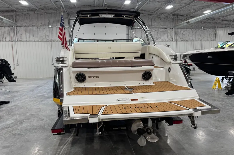 Slide: The Image of 2012 Cobalt 276 boat in showroom, featuring teak swim platform and American flag. - 5