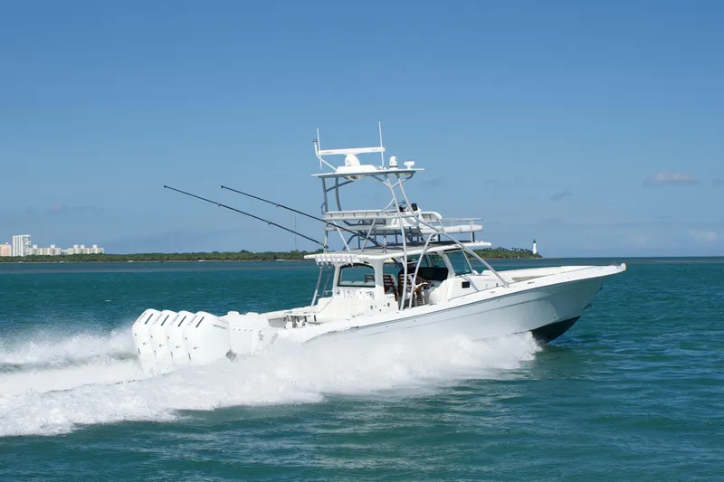 Slide: The Image of 2023 HCB 53 Sueños boat cruising on blue ocean with cityscape and lighthouse in background. - 5