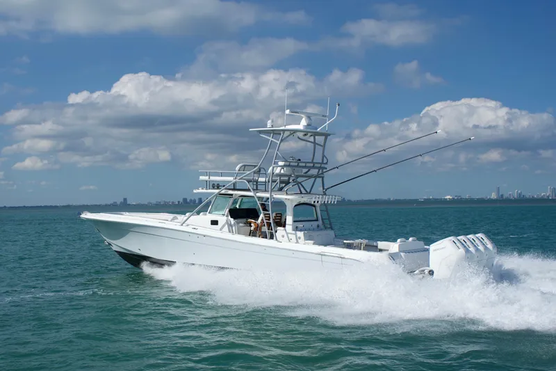 Slide: The Image of 2023 HCB 53 Sueños boat cruising on blue ocean with city skyline in background. - 6