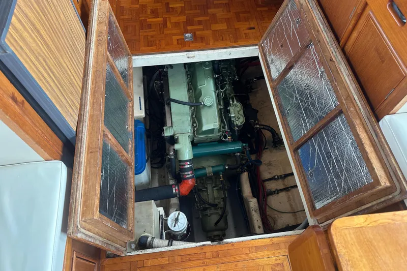 Slide: The Image of 1976 Grand Banks Sedan engine compartment with wooden cabinetry and visible engine components. - 10