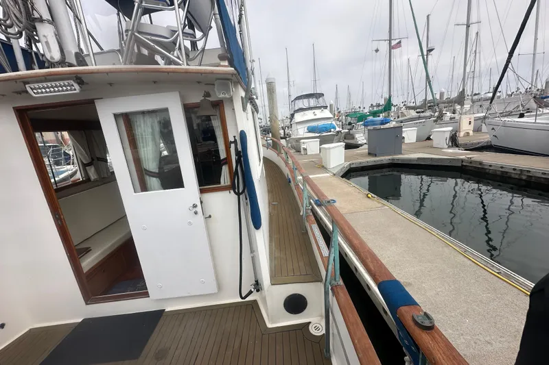 Slide: The Image of 1976 Grand Banks Sedan docked at marina, showcasing wooden deck and open cabin door. - 13