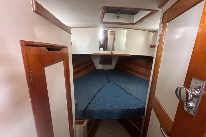Slide: The Image of 1976 Grand Banks Sedan cabin interior with wooden accents and blue bedding. - 2