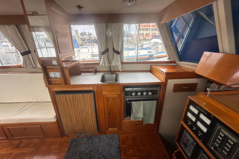 Slide: The Image of 1976 Grand Banks Sedan interior with kitchen, sink, stove, and marina view through windows. - 6