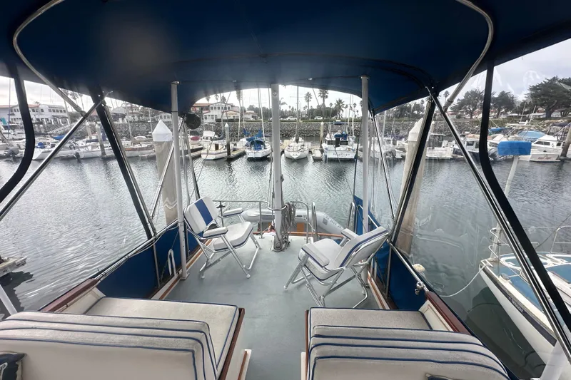 Slide: The Image of 1976 Grand Banks Sedan boat interior with marina view, featuring seating and canopy. - 9