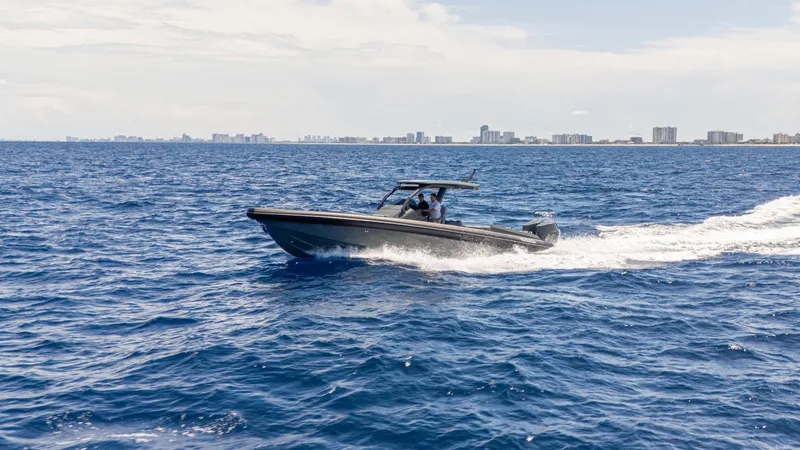 Slide: The Image of Skipper-BSK 38 boat cruising on ocean, city skyline in background, 2025 model. - 11