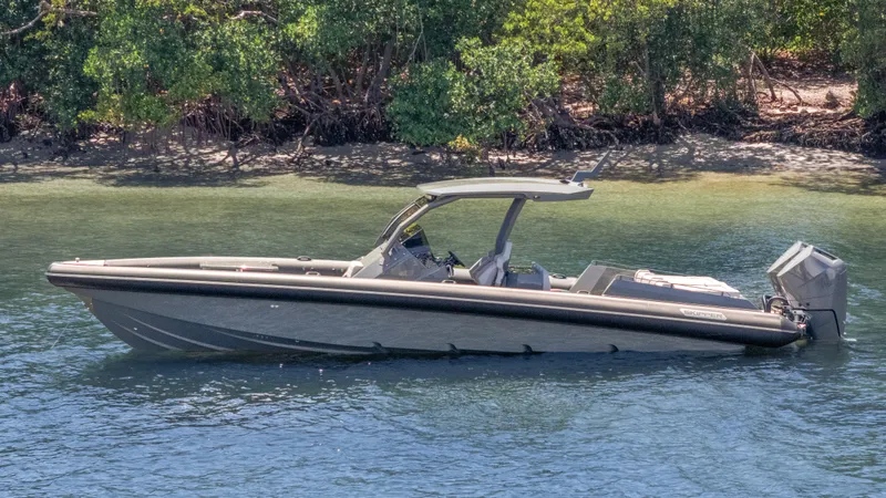 Slide: The Image of 2025 Skipper-BSK 38 boat on calm water near lush green shoreline. - 29