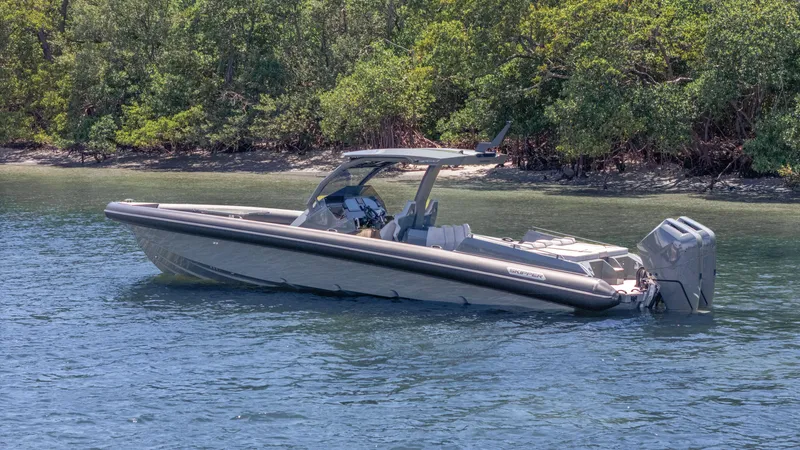 Slide: The Image of 2025 Skipper-BSK 38 boat on calm water near lush green shoreline. - 27