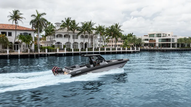 Slide: The Image of 2025 Skipper-BSK 38 boat cruising on a scenic waterfront with luxury homes and palm trees. - 37