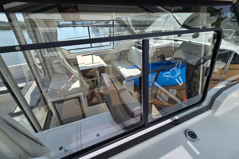Slide: The Image of 2023 Jeanneau NC Sport 795 Series 2 interior view through window, showcasing seating and helm. - 4