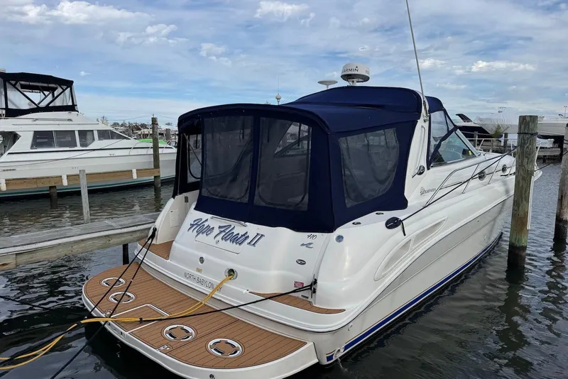 Slide: The Image of 2000 Sea Ray 410 Sundancer docked, featuring a blue canopy and teak deck. - 2