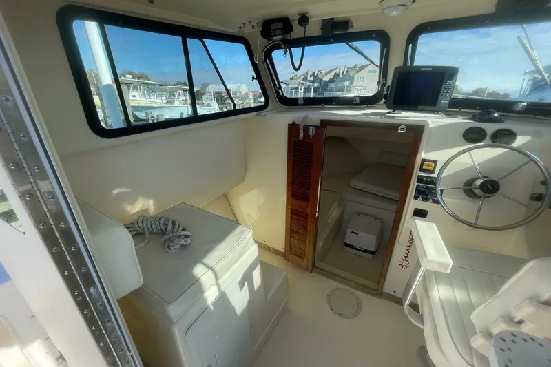 Slide: The Image of Interior of a 2001 Parker 2520 Sport Cabin boat with steering wheel and seating. - 11