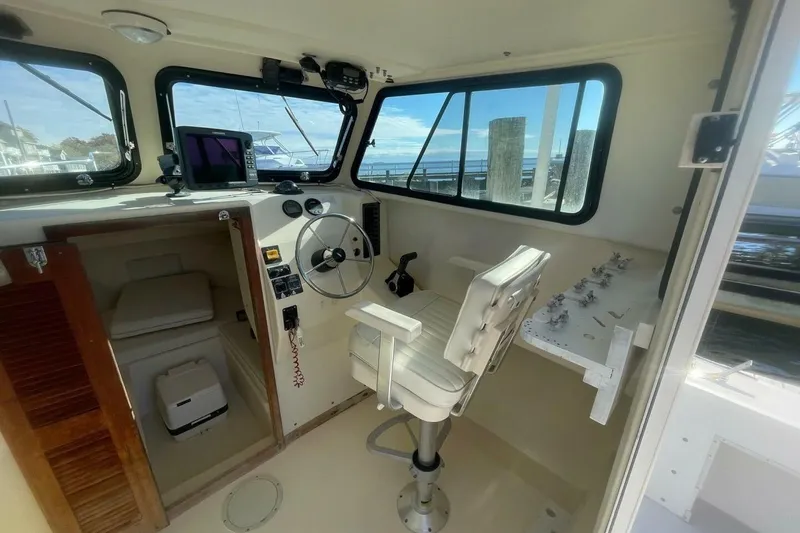 Slide: The Image of Interior of a 2001 Parker 2520 Sport Cabin boat with steering wheel and seating. - 12