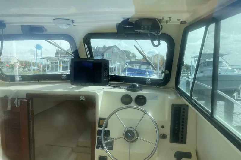 Slide: The Image of Interior view of a 2001 Parker 2520 Sport Cabin boat with steering wheel and navigation equipment. - 8