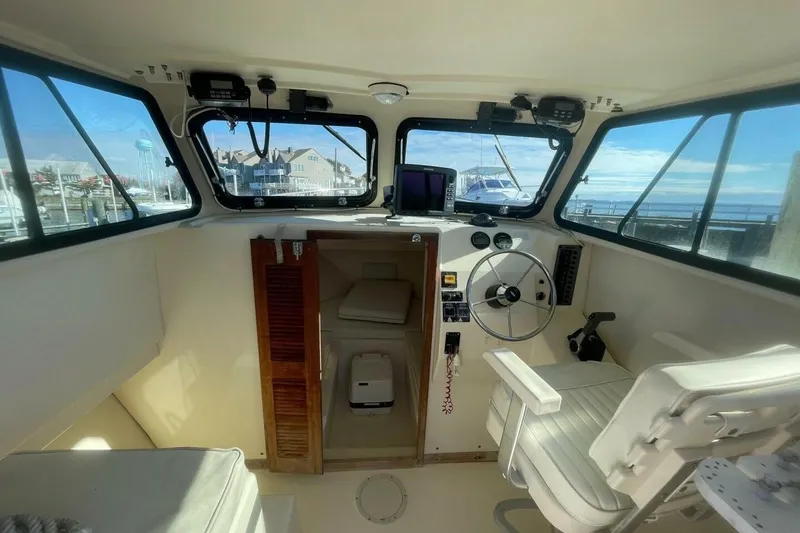 Slide: The Image of Interior of a 2001 Parker 2520 Sport Cabin boat with steering wheel and seating. - 9