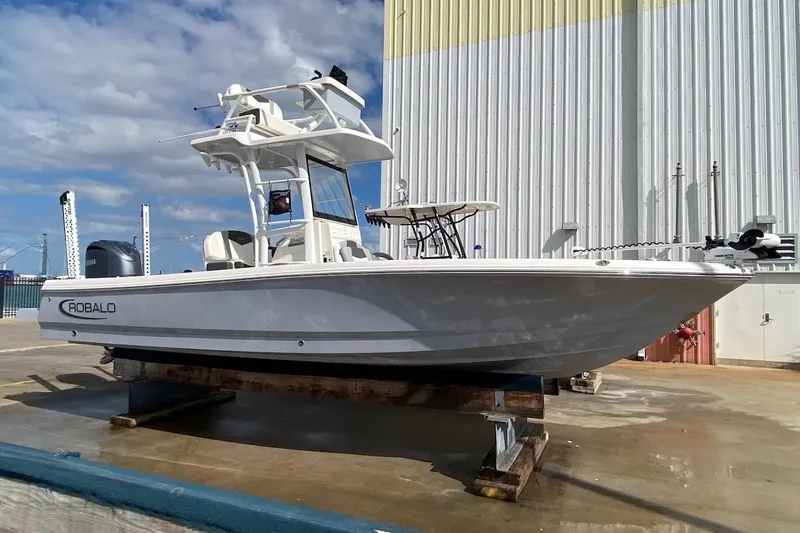 Slide: The Image of 2023 Robalo 246 Cayman SD boat on dry dock, white hull, clear sky background. - 11