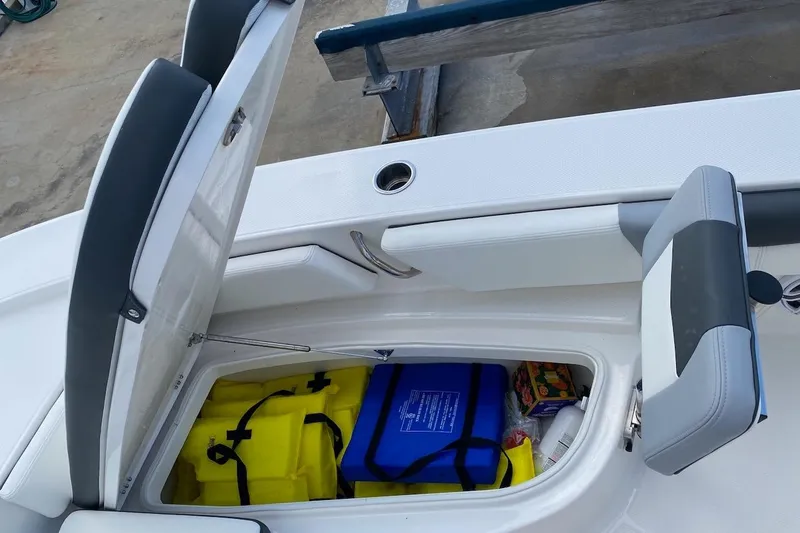 Slide: The Image of 2023 Robalo 246 Cayman SD boat storage compartment with life jackets and safety gear. - 18