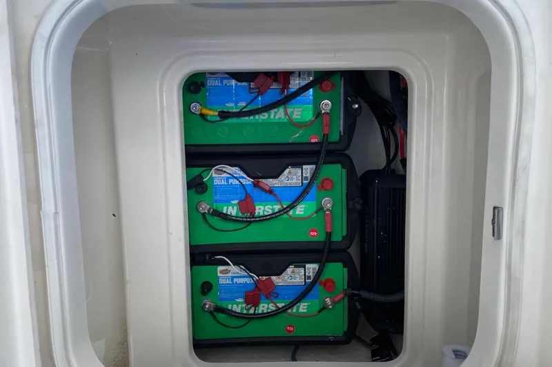 Slide: The Image of 2023 Robalo 246 Cayman SD boat battery compartment with three green batteries. - 21