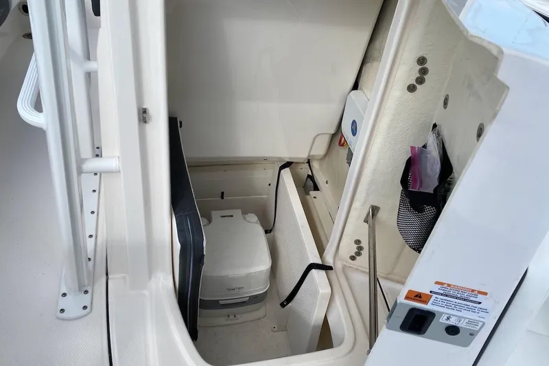 Slide: The Image of 2023 Robalo 246 Cayman SD boat interior storage compartment with portable toilet. - 24