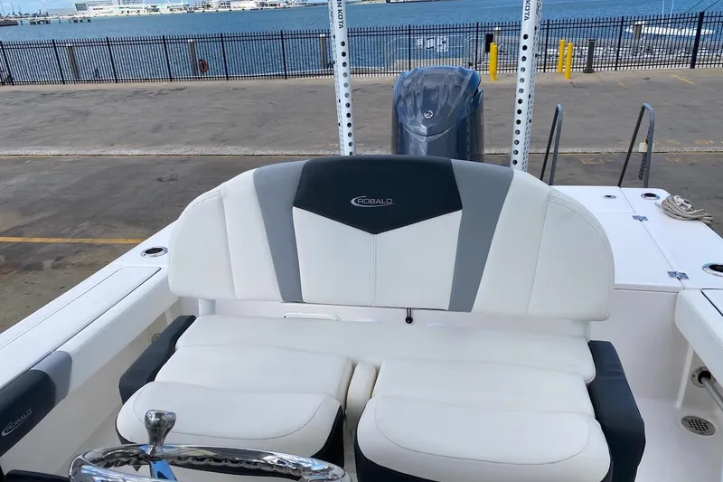Slide: The Image of 2023 Robalo 246 Cayman SD boat interior with white and gray seating, dockside view. - 29